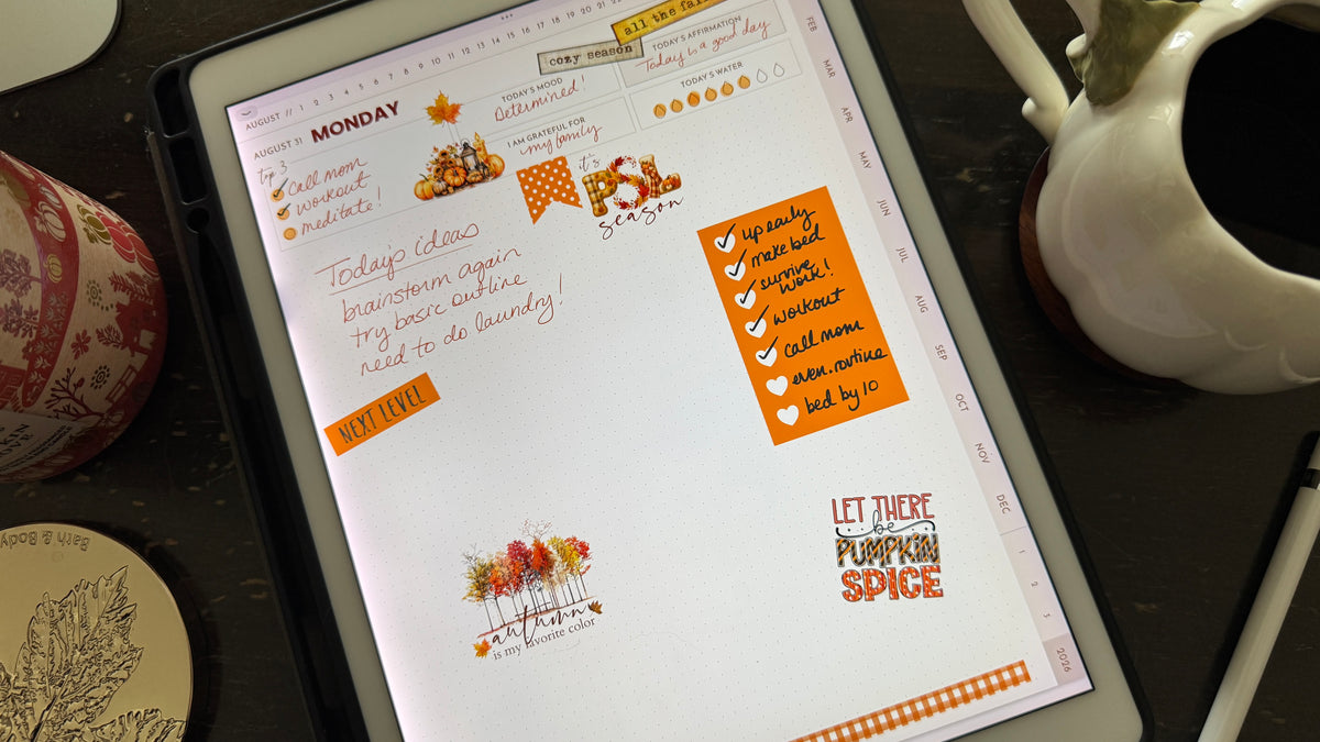 A photo of a digital planner page shown on an iPad decorated with autumn stickers and handwriting. There is a white pumpkin mug and fall candle surrounding the iPad.